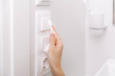 Temizlik düğmeleri ve prizleri mikrofiber bezle temizliyorum. Kadın eli temizlik için ıslak mendil kullanıyor. Hastane ve halka açık alanlarda korona virüsüne karşı yüzeylerin sterilize edilmesi