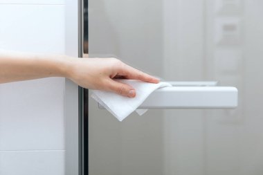 Cam kapı kollarını antiseptik ıslak mendille temizliyorum. Ev kapısı bağlantısını temizlemek için havlu kullanan kadın eli. Hastane ve halka açık alanlarda korona virüsüne karşı yüzeylerin sterilize edilmesi