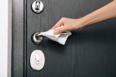 Siyah kapı kollarını antiseptik ıslak mendille temizliyorum. Ev kapısı bağlantısını temizlemek için havlu kullanan kadın eli. Hastane ve halka açık alanlarda korona virüsüne karşı yüzeylerin sterilize edilmesi