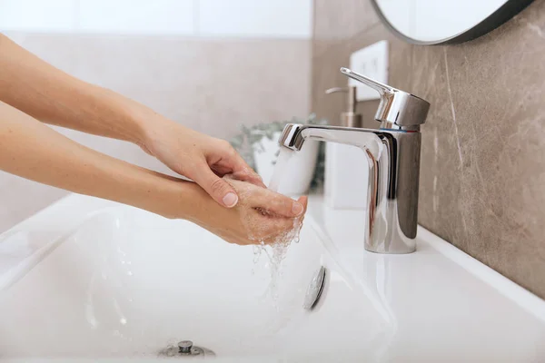 Se laver les mains sous le robinet d'eau courante. Se laver les mains en frottant avec du savon pour prévenir le virus de la couronne, l'hygiène pour arrêter la propagation du virus de la couronne dans les toilettes publiques. Concept d'hygiène détail des mains — Photo