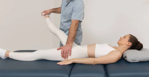 Klinikte diz ağrısı giderici. Doktor fizyoterapist hasta bacağına tedavi uyguluyor. Terapist bacak ve baldır masajı yapıyor. Osteopati, Kayropraktik bacak ayarlaması. Kayropraktik tedavi