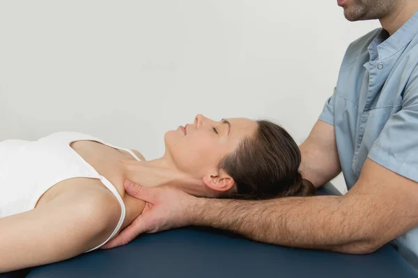 Female patient receiving osteopathic neck and shoulder treatment. Therapist manipulating back of head and chest. A girl receiving CST treatment. Osteopathic manipulation and therapy