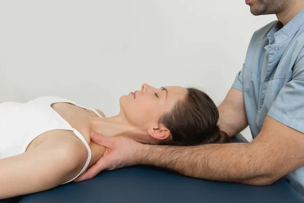 Osteopatik boyun ve omuz tedavisi gören kadın hasta. Kafa ve göğsün arkasını manipüle eden bir terapist. CST tedavisi gören bir kız. Osteopatik yönlendirme ve terapi