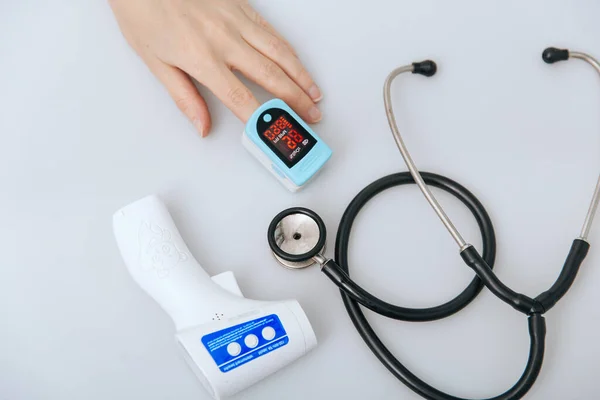 Stetoskop, nabız oksimetresi ve beyaz arka planda termometre tabancası. Soğuk algınlığı veya grip tedavisi. Phonendoskop. Virüs belirtileri için vücut sıcaklığını ölçmek için kızılötesi izometrik termometre tabancası.