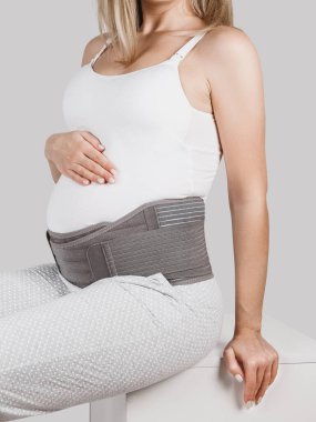 Hamilelik öncesi hamilelik kemeri takmış hamile bir kadın. Ortopedik karın desteği bel, sırt, karın bandı. Hamilelik için karın korsesi ya da bant. Yatay web pankartı. Hamile modelin gövdesi