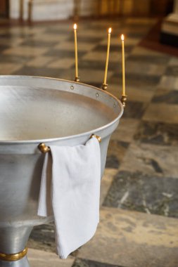 Baptismal font. Interior and Altar in the temple Orthodox Church. Christianity. Festive interior decoration with burning candles and icon. The ceremony of infant baptism.