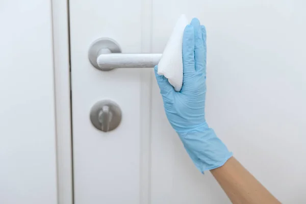 用防腐剂湿擦拭蓝色手套清洁黑色门把手。女人用毛巾洗手.在医院和公共场所清洁表面，防止感染日冕病毒 — 图库照片