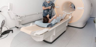 Tomografi tomografisi ya da hastanede MRI taraması olan doktor, hemşire ve hasta. Radyografi bölümünün içi. Beyaz odada teknolojik olarak gelişmiş ekipmanlar var. Manyetik rezonans tanılama makinesi