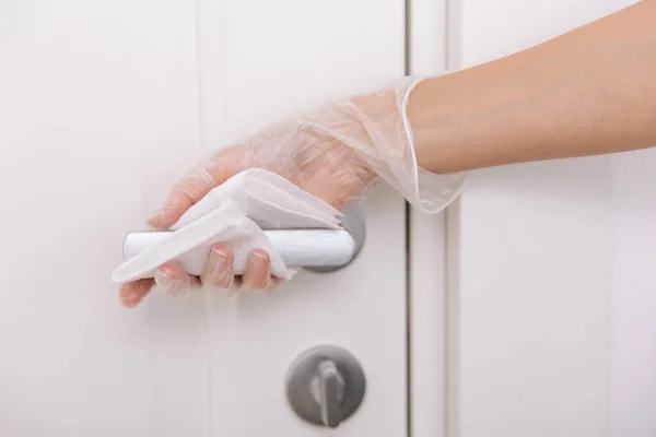 用湿擦拭和白手套清洁门把手.女人用毛巾清洁家房间的门链.在医院和公共场所清洁表面，防止感染日冕病毒 — 图库照片
