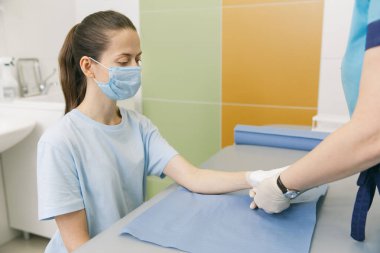 İlk yardım için bileğine dolanmış bir doktor. Hastaların ellerine bandaj uygulaması, ilk yardım konseptleri ve bilek yaralanması tedavisi. Hastanın elinde tıbbi bandaj var. Bilek ağrısı.