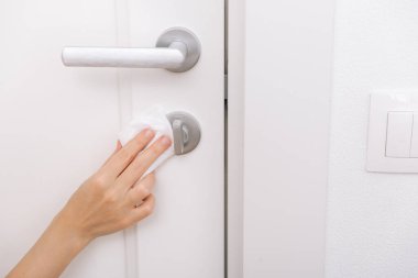 Antiseptik ıslak mendil ve eldivenle kapı kolları temizleniyor. Hastane ve kamusal alanlarda korona virüsüne karşı korunma yüzeylerini sterilize edin. Kadın eli temizlik için havlu kullanıyor.