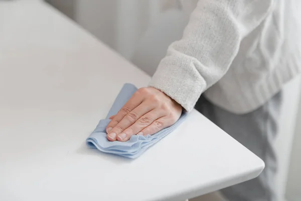 Cleaning the table with a blue microfiber cloth. Sanitize surfaces prevention in hospital and public spaces against coronavirus. Woman hand using wet wipe at home. Cleaning the room — Stock Photo, Image