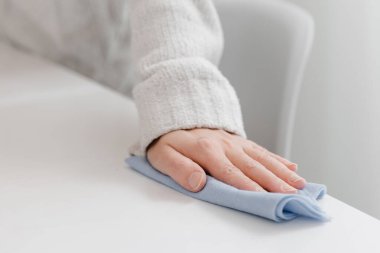 Masayı mavi bir mikrofiber bezle temizliyorum. Hastane ve halka açık alanlarda koronavirüse karşı korunma yüzeylerini sterilize edin. Evde ıslak mendil kullanan bir kadın eli. Odayı temizliyorum.