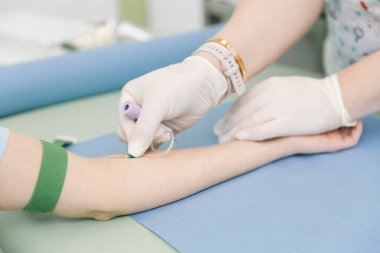 Tedavi odasındaki bir damardan kan testi alıyorum. Hemşire şırıngayı hastanın eline iğneyle batırıyor. Kan bağışı sırasında enjeksiyon yerine baskı yapılmış. Kanlı tüp