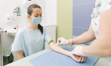 Tedavi odasındaki bir damardan kan testi alıyorum. Hemşire şırıngayı hastanın eline iğneyle batırıyor. Kan bağışı sırasında enjeksiyon yerine baskı yapılmış. Kanlı tüp
