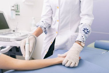 Doktor eline ultrason yapıyor. Yakın plan. Doktor ultrason sonuçlarını hastaya gösterir. Tıbbi ultrason taraması. Kas gevşemesi için botoks enjeksiyonunun rehabilitasyon uygulaması