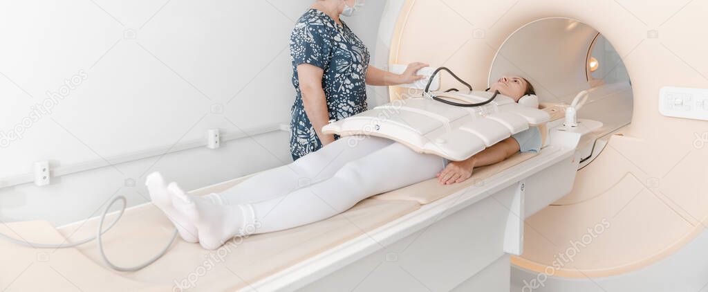 Doctor or nurse and patient with tomography CT or MRI Scan in hospital. Interior of radiography department. Technologically advanced equipment in white room. Magnetic resonance diagnostics machine