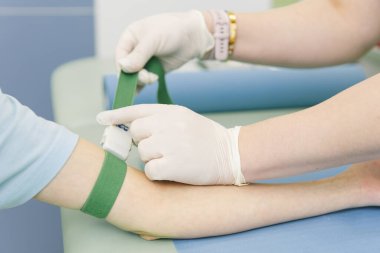Tedavi odasındaki bir damardan kan testi alıyorum. Hemşire şırıngayı hastanın eline iğneyle batırıyor. Kan bağışı sırasında enjeksiyon yerine baskı yapılmış. Kanlı tüp