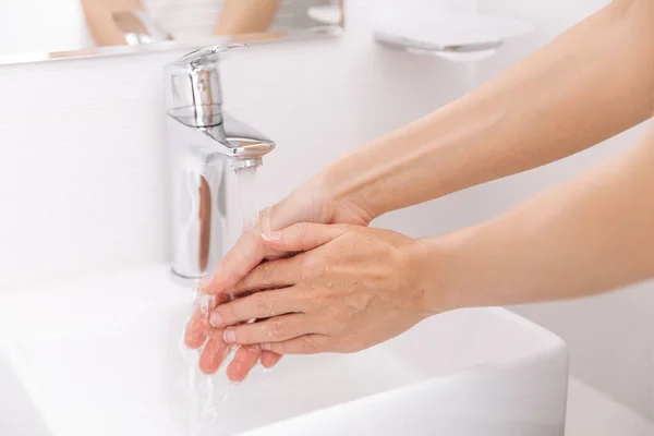 Hände waschen unter dem fließenden Wasserhahn. Händewaschen mit Seife zur Vorbeugung des Coronavirus, Hygiene gegen die Ausbreitung des Coronavirus in öffentlichen Waschräumen. Hygienekonzept Hand in Hand — Stockfoto