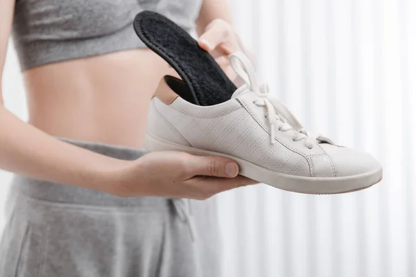 Mulher colocando palmilha ortopédica no sapato em casa. Menina de esportes encaixe palmilha ortopédica dentro de casa, de perto. Banner de cuidados com os pés. Correção de pés chatos. Tratamento e prevenção de doenças dos pés — Fotografia de Stock