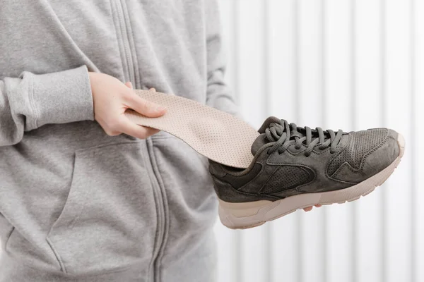 Mujer poniendo plantilla ortopédica en el zapato en casa. Chica deportiva ajustando plantilla ortopédica en el interior, de cerca. Banner de cuidado del pie. Corrección de pies planos. Tratamiento y prevención de enfermedades del pie — Foto de Stock