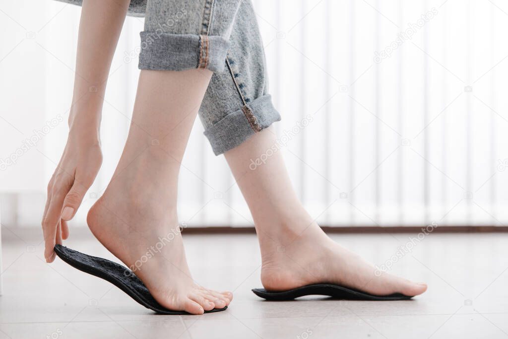Woman fitting orthopedic insole indoors, close up. Girl holding an insole next to foot at home. Orthopedic insoles. Foot care banner. Flat Feet Correction. Treatment and prevention of foot diseases