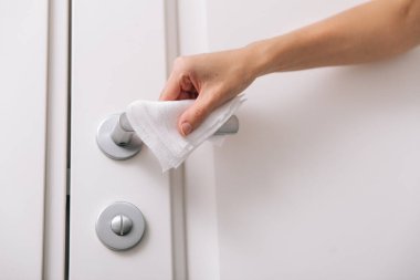 Antiseptik ıslak mendil ve eldivenle kapı kolları temizleniyor. Hastane ve kamusal alanlarda korona virüsüne karşı korunma yüzeylerini sterilize edin. Kadın eli temizlik için havlu kullanıyor.