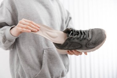 Spor giyimli, spor ayakkabılı, tabanlı, spor ayakkabılı bir kadın. Ortopedik tabanı ayakkabıya takan kadın. Ayak bakımı afişi. Düz Ayak Düzeltme