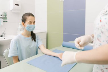 Tedavi odasındaki bir damardan kan testi alıyorum. Hemşire şırıngayı hastanın eline iğneyle batırıyor. Kan bağışı sırasında enjeksiyon yerine baskı yapılmış. Kanlı tüp