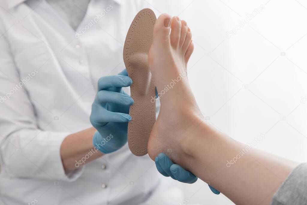 Doctor hands hold an orthopedic insole. Orthopedist tests the medical device. Orthopedic insoles on a white background. Foot care, comfort for the feet. Treatment and prevention of flat feet and foot