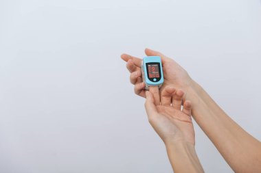 Nabız oksimetresi, beyaza izole edilmiş bir doktorun eliyle. Kişilerin oksijen doygunluğunu ölçmek için taşınabilir dijital cihaz kavramı. Oksijen doygunluğu, nabız oranı ve oksijen seviyeleri ölçülüyor.