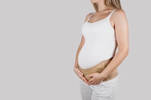 Pregnant woman belly in prenatal pregnancy maternity belt. Orthopedic abdominal support waist, back, abdomen band. Belly brace or band for pregnancy. Horizontal web banner. Torso of pregnant model
