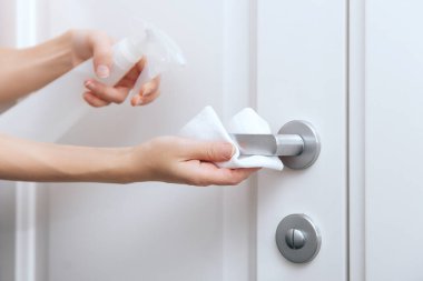 Beyaz kapı kollarını antiseptik ıslak mendil ve dezenfektanla temizliyorum. Hastane ve halka açık alanlarda Corona virüsüne karşı dezenfeksiyon. Kadın eli temizlik için havlu kullanıyor.
