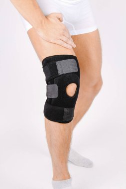 Diz Destek Kolu beyaz arka planda izole edilmiş bir bacak üzerinde. Elastik ortopedik ortopedi. Diz saplantısı, yaralanma ve ağrı için anatomik destek. Koruyucu diz eklemi bandaj kolu. Travma, rehabilitasyon.