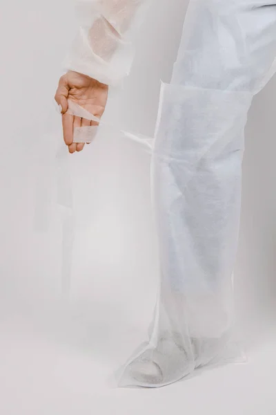 A nővér eldobható köpenyt és eldobható cipőt visel. Az orvos fehér orvosi cipőt vesz fel, közelit. Ruhák kórházi látogatásokhoz vagy orvosi egyenruha koncepció. Cipővédelem — Stock Fotó