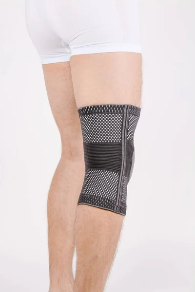 Knee Support Brace on leg isolated on white background. Elastic orthopedic orthosis. Anatomic braces for knee fixation, injuries and pain. Protective knee joint bandage sleeve. Trauma, rehabilitation