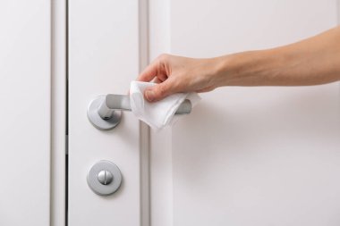 Antiseptik ıslak mendil ve eldivenle kapı kolları temizleniyor. Hastane ve kamusal alanlarda korona virüsüne karşı korunma yüzeylerini sterilize edin. Kadın eli temizlik için havlu kullanıyor.