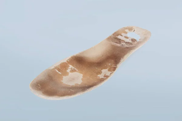 Gamla och shabby ortopediska sulor isolerade på blå bakgrund. Smutsiga lädersulor. Slit ut saker med hål. Innersulor av skor. Top view banner närbild — Stockfoto