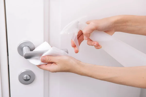 Cleaning white door handles with an antiseptic wet wipe and sanitizer spray. Disinfection in hospital and public spaces against corona virus. Woman hand using towel for cleaning home room door link — Stock Photo, Image