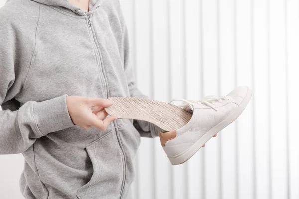 Woman putting orthopedic insole into shoe at home. Sports girl fitting orthopedic insole indoors, close up. Foot care banner. Flat Feet Correction. Treatment and prevention of foot diseases — Stock Photo, Image