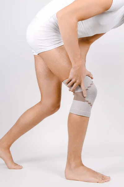 Cinta de apoio do joelho na perna isolada no fundo branco. Órtese ortopédica elástica. Aparelhos anatômicos para fixação do joelho, lesões e dor. Manga protetora da ligadura da articulação do joelho. Trauma, reabilitação — Fotografia de Stock