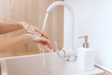 Akan su musluğunun altında ellerini yıkamak. Corona virüsünün önlenmesi için sabunla ellerini ovuşturmak, korona virüsü bulaştırmamak için hijyen. Ya da umumi tuvalette. Hijyen konsepti el detayı