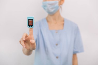Nabız oksimetresi, beyaza izole edilmiş bir doktorun eliyle. Kişilerin oksijen doygunluğunu ölçmek için taşınabilir dijital cihaz kavramı. Oksijen doygunluğu, nabız oranı ve oksijen seviyeleri ölçülüyor.