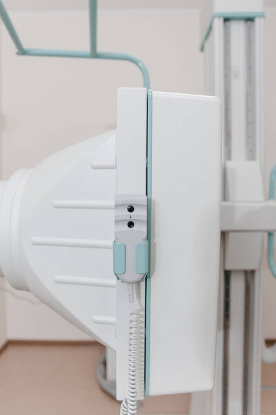 Больничная радиологическая комната. Флюорографическое устройство для рентгенографии. Врач-рентгенолог в халате настраивает рентгеновский аппарат для рентгенографии. Медицинское оборудование. Сканирование груди, сердца или легких в клинике