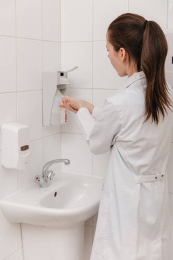 Beyaz üniformalı doktor ellerini dezenfekte ediyor. Cerrah el yıkama hastane konsepti. Hemşire ellerini dezenfeksiyon için dezenfektan, şeker ya da alkol çözeltisi ile yıkıyor..