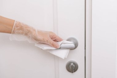 Islak mendil ve beyaz eldivenlerle kapı kolları. Ev kapısı bağlantısını temizlemek için havlu kullanan kadın eli. Hastane ve halka açık alanlarda korona virüsüne karşı yüzeylerin sterilize edilmesi.