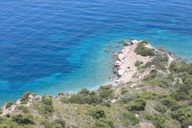 Yeşil çimenleri, mavi gökyüzü, deniz ya da okyanusu olan güzel bir deniz manzarası. Pankart, duvar kağıdı ya da kartpostal için doğa manzarası. Dağlık arazi sisli.