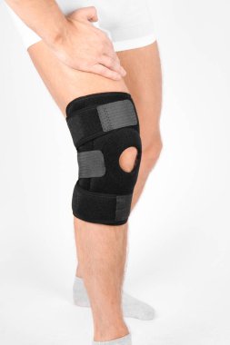 Diz Destek Kolu beyaz arka planda izole edilmiş bir bacak üzerinde. Elastik ortopedik ortopedi. Diz saplantısı, yaralanma ve ağrı için anatomik destek. Koruyucu diz eklemi bandaj kolu. Travma, rehabilitasyon..