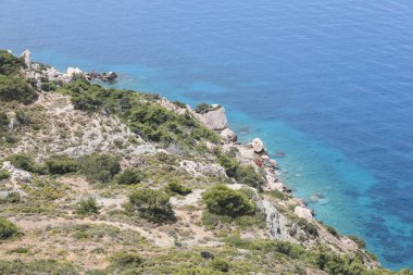 Yeşil çimenleri, mavi gökyüzü, deniz ya da okyanusu olan güzel bir deniz manzarası. Pankart, duvar kağıdı ya da kartpostal için doğa manzarası. Dağlık arazi sisli.