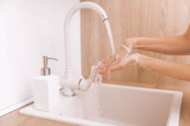 Akan su musluğunun altında ellerini yıkamak. Corona virüsünün önlenmesi için sabunla ellerini ovuşturmak, korona virüsü bulaştırmamak için hijyen. Ya da umumi tuvalette. Hijyen konsepti el detayı.
